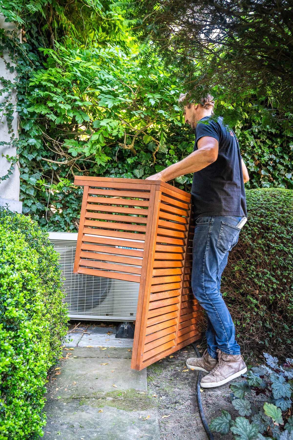 Daikin-buitenunit achter een geopend hardhouten rooster in Brugge